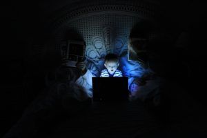 Niño con el ordenador en la cama